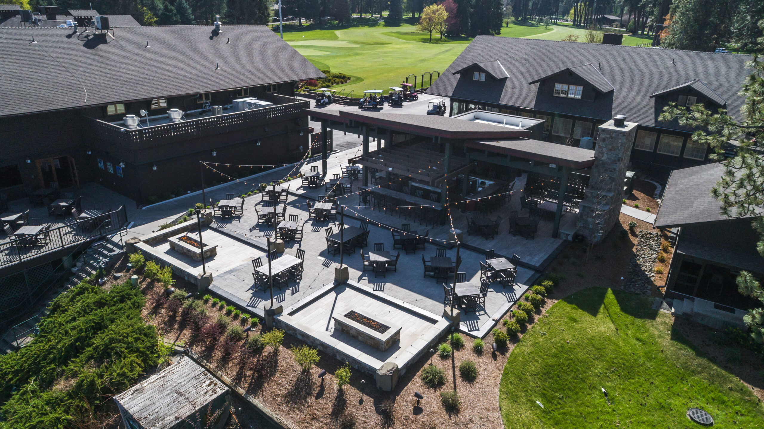 Outdoor patio and bar at Hayden Lake Country Club featuring stone fire pits, seating, and golf course views, built by Ginno Construction.